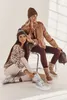 Two women posing in winter fashion, one sitting and one kneeling, with winter boots and accessories. Produktbild-Vorschau
