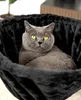 A gray cat is resting in a black, plush cat bed. Produktbild-Vorschau