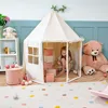 A young girl plays inside a cream-colored tent with building blocks, surrounded by toys in a child's room. Produktbild-Vorschau