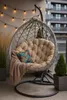 A hanging chair with cushions and a blanket on a balcony, decorated with string lights. Produktbild-Vorschau