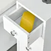 A white bathroom storage unit with an open drawer containing a yellow object. Voir les images du produit