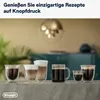 Several coffee cups filled with different coffee drinks are displayed on a counter in front of a blurred background with a plant and furniture. Produktbild-Vorschau