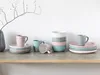 A collection of ceramic dishes and mugs arranged on a wooden shelf against a white background. Náhľad obrázku produktu