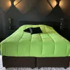 A bed with a lime green comforter and black pillows in a modern bedroom. Produktbild-Vorschau