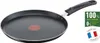 A black frying pan with a red heat indicator in the center and a black handle, set against a white background. To the right of the pan are two graphic overlays: a green rectangle with white text and a circular badge with the French flag and text. Produktbild-Vorschau
