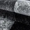 A close-up view of stacked rugs with a speckled pattern in black, gray, and white. Podgląd zdjęcia produktu