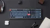 A keyboard and accessories are laid out on a dark surface. Produktbild-Vorschau