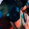 A close-up shot of a person adjusting a pair of gaming headphones. Anteprima dell’immagine prodotto