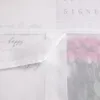 A close-up view of a white sheer curtain with a floral print visible through it, and handwritten text on the curtain itself. Produktbild-Vorschau