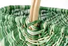 A close-up shot of the woven handle and rim of a green and white basket. Náhled obrázku produktu