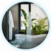 A modern bathroom with a bathtub, bidet, and a bathrobe hanging on the wall, with plants and a window view of a city building. Produktbild-Vorschau