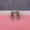 A close-up view of two zippers on a U-shaped pillow, showing the gray and pink fabric. Náhled obrázku produktu