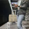 A person is standing on a train platform with luggage, looking at their phone. Náhľad obrázku produktu