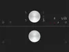 Close-up of a black induction hob control panel with two silver rotary knobs and digital displays. Podgląd zdjęcia produktu