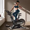 A woman is exercising on a stationary bike in a room. Náhled obrázku produktu
