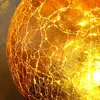 A close-up of a cracked glass sphere illuminated from within. Produktbild-Vorschau