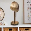 A blonde wig on a wooden stand, placed on a shelf with a globe and baskets. Produktbild-Vorschau