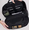An open black backpack with various items inside, including a laptop, tablet, and a small umbrella. Produktbild-Vorschau