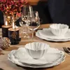 A festive table setting with white plates, bowls, wine glasses, and candles. Voir les images du produit