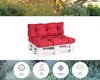 A red pallet sofa cushion set on a white background, with a blurred garden scene above and foliage below. Voir les images du produit