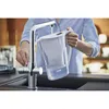 A person is filling a water filter pitcher from a kitchen faucet. Produktbild-Vorschau
