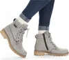 A person wearing blue jeans and white socks is wearing a pair of gray lace-up ankle boots. Anteprima dell’immagine prodotto