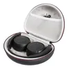 A black headset is stored in an open, round, black storage case with a red trim. The inside of the case is lined with gray fabric, and a mesh pocket holds a charging cable. Produktbild-Vorschau