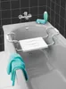 A bathtub with a bath seat installed, a towel draped over the side, and a bottle of soap and sponge on the edge. Náhled obrázku produktu