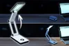 A split image showing a white LED desk lamp in two different states: folded and unfolded, connected to a laptop. Produktbild-Vorschau