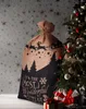 A Christmas sack with a festive design is placed next to a decorated Christmas tree and wrapped gifts. Anteprima dell’immagine prodotto