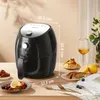 A black air fryer is displayed on a wooden table, surrounded by food and a glass of wine, suggesting a lifestyle setting. Produktbild-Vorschau