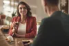 Two people are sitting at a table, with one woman holding a small cup of coffee. Anteprima dell’immagine prodotto