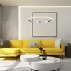 A modern living room with a yellow sectional sofa, white coffee tables, and a large circular pendant light. Produktbild-Vorschau