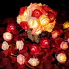 A string of rose-shaped LED lights is arranged in a basket and scattered around on a bed of red rose petals. Produktbild-Vorschau