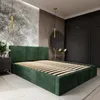 A bedroom scene featuring a green upholstered bed frame with a slatted base, set against a wall with a nature-themed mural and wooden paneling. A dark wardrobe and a round mirror are visible in the background. Náhled obrázku produktu