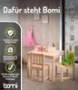 A child's wooden table and chairs set with a pink tutu and a green teddy bear, set against a wood-paneled wall. Produktbild-Vorschau
