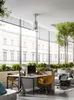 A modern office space with large windows, plants, and workstations. Anteprima dell’immagine prodotto