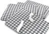 Several folded fabric items with a checkered pattern are stacked on a white background. Produktbild-Vorschau