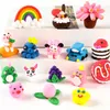 A collection of small, colorful clay figures arranged on white shelves. Náhled obrázku produktu