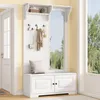 A white entryway furniture set with a bench, storage cabinets, hooks, and a shelf, placed in a hallway next to a door and a window. Produktbild-Vorschau