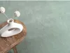 A white vase with decorative spheres on sticks sits on a wooden table next to a light green carpet. Produktbild-Vorschau