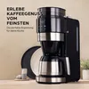 A black and silver coffee maker with a built-in grinder and thermal carafe, placed on a countertop next to plates and a small container of sugar. Text overlays describe the product in German. Produktbild-Vorschau
