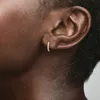 Close-up of a person's ear wearing a small hoop earring. Voir les images du produit