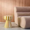 A striped side table next to a textured sofa. Produktbild-Vorschau