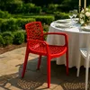 An outdoor dining setting with a red chair in the foreground and a table set for a meal in the background. Produktbild-Vorschau