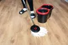 A person is mopping a wooden floor with a spin mop and bucket. Produktbild-Vorschau