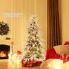A decorated Christmas tree stands in a cozy living room setting, with a fireplace and gifts. Podgląd zdjęcia produktu