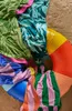 A pile of colorful beach towels and an inflatable ring are spread out on the sand. Produktbild-Vorschau