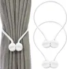 A pair of magnetic curtain clips holding back a gray curtain, and a separate pair of clips on a white background. Náhľad obrázku produktu