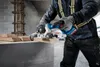 A person is using a cordless circular saw to cut a piece of wood. There is dust in the air. Produktbild-Vorschau